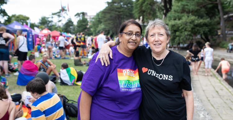 Two women at a pride march with their arms round each other